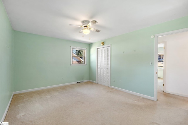 empty room with visible vents, carpet floors, a ceiling fan, and baseboards