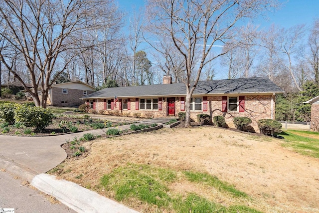 ranch-style home featuring driveway, a chimney, and brick siding