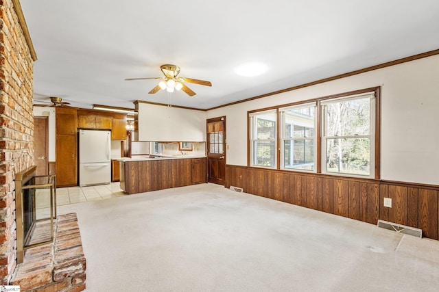 unfurnished living room featuring a brick fireplace, a wainscoted wall, and wooden walls