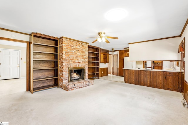 unfurnished living room with a ceiling fan, a brick fireplace, light carpet, and crown molding