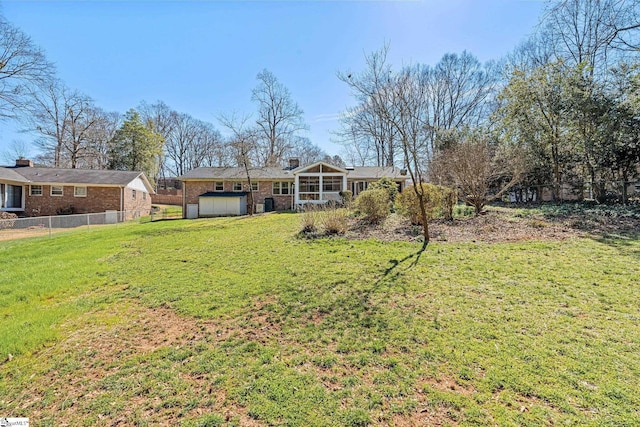 view of yard featuring a garage, a sunroom, and fence