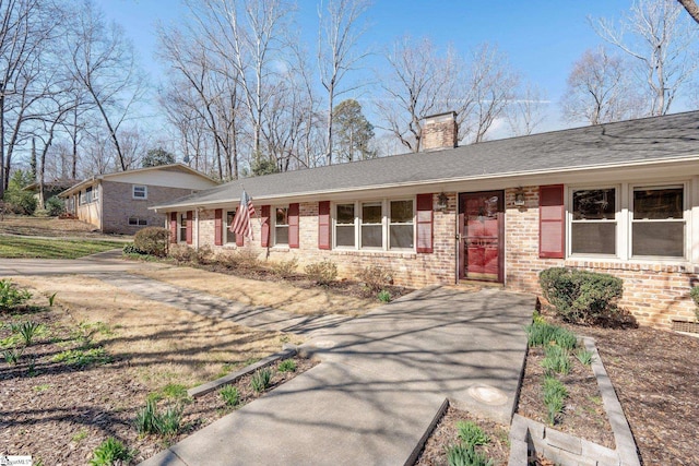 single story home with a chimney and brick siding