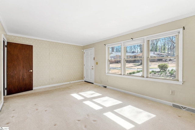 empty room with visible vents, ornamental molding, carpet flooring, baseboards, and wallpapered walls