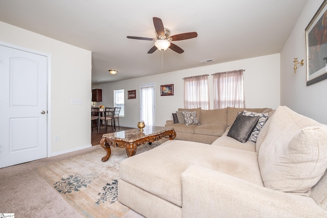 living area featuring carpet floors, baseboards, visible vents, and a ceiling fan