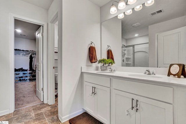 full bathroom featuring a stall shower, visible vents, a sink, and double vanity