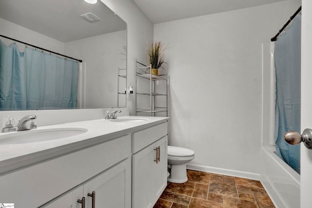 bathroom featuring baseboards, a sink, toilet, and double vanity