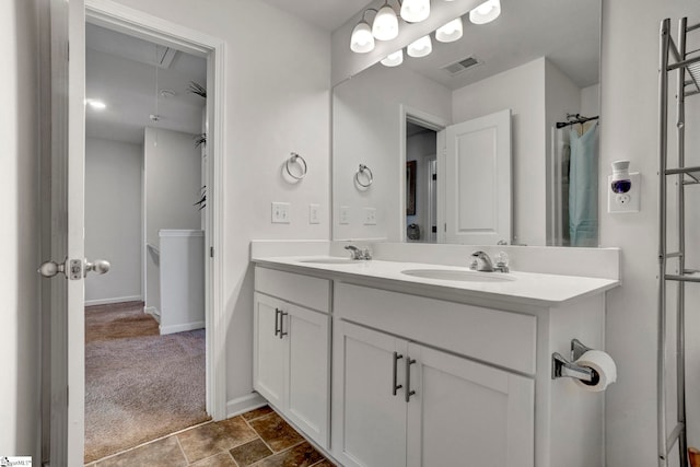 bathroom featuring double vanity, a sink, visible vents, and baseboards