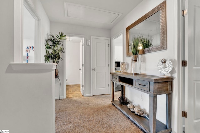 hallway with carpet floors, attic access, and baseboards