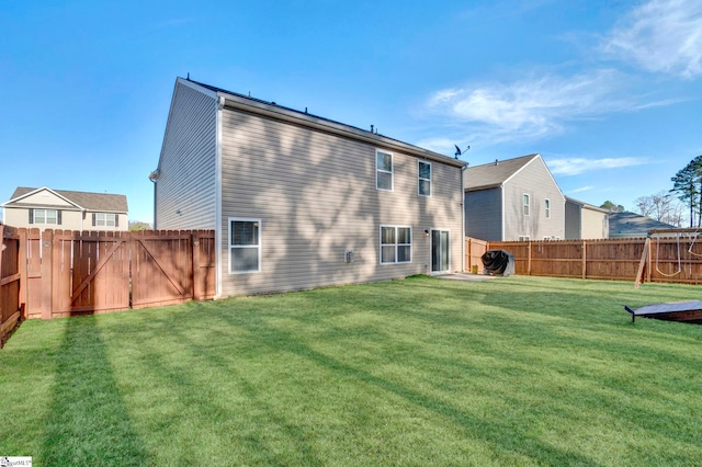 back of property with a fenced backyard and a lawn