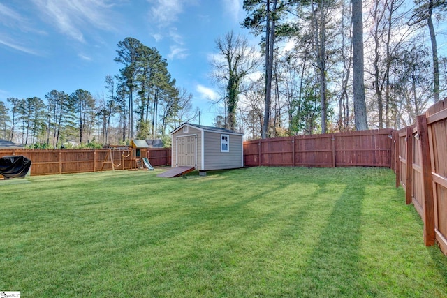 view of yard with a shed, a fenced backyard, a playground, and an outdoor structure