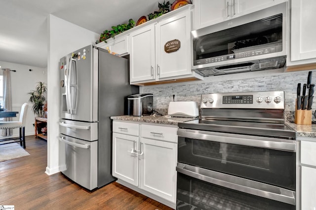 kitchen with dark wood-style floors, stainless steel appliances, tasteful backsplash, white cabinets, and light stone countertops