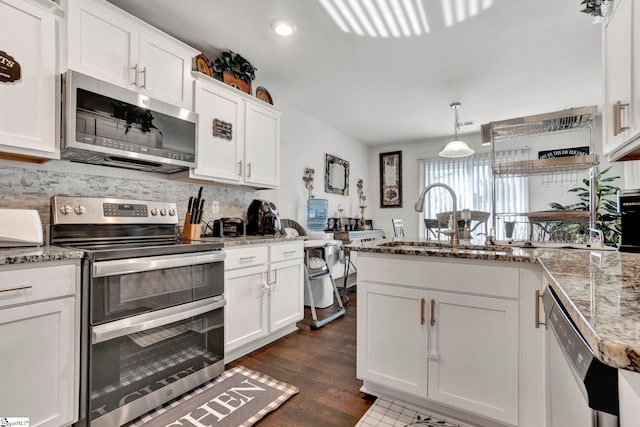 kitchen with stainless steel appliances, a peninsula, a sink, white cabinetry, and decorative backsplash