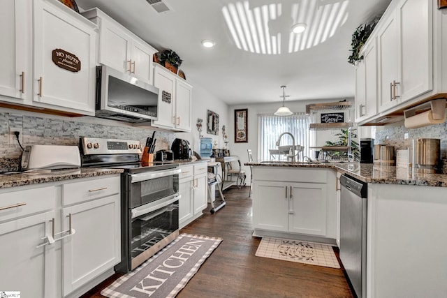 kitchen featuring stainless steel appliances, a peninsula, visible vents, white cabinetry, and dark wood finished floors