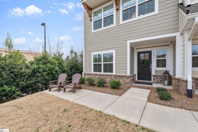 view of exterior entry with a patio and brick siding