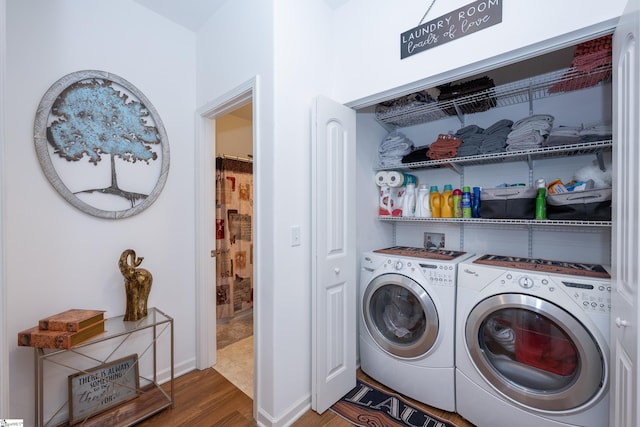 laundry room with laundry area, baseboards, washing machine and clothes dryer, and wood finished floors