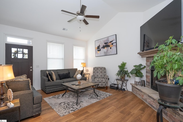 living room with vaulted ceiling, visible vents, a fireplace, and wood finished floors