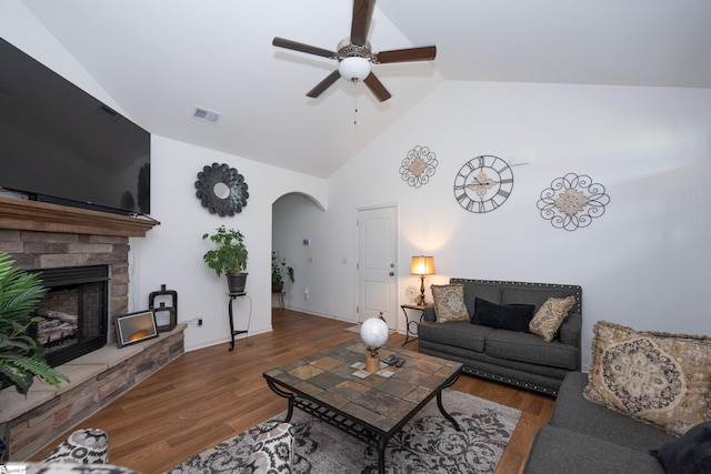 living area with arched walkways, visible vents, a fireplace, and wood finished floors