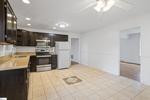 kitchen featuring light stone counters, crown molding, light tile patterned floors, stainless steel appliances, and a sink