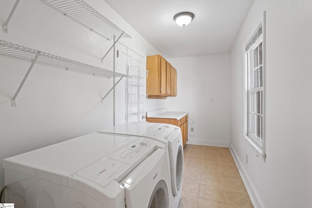 washroom with light tile patterned floors, laundry area, washing machine and clothes dryer, and baseboards