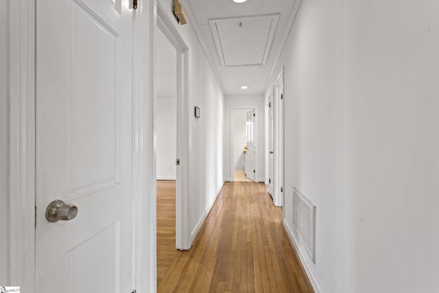 corridor featuring baseboards, hardwood / wood-style flooring, visible vents, and attic access