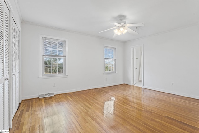 unfurnished bedroom with ornamental molding, visible vents, light wood-style flooring, and multiple windows