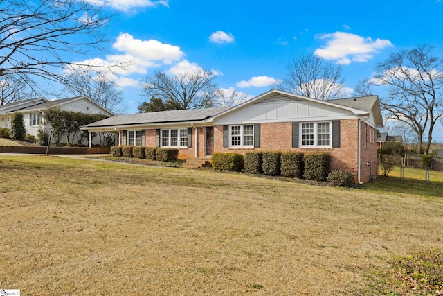 ranch-style house with brick siding, board and batten siding, a front yard, and fence