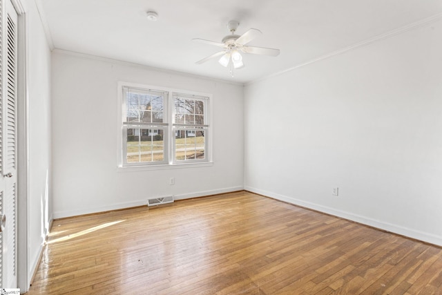 empty room with light wood finished floors, visible vents, baseboards, ceiling fan, and ornamental molding