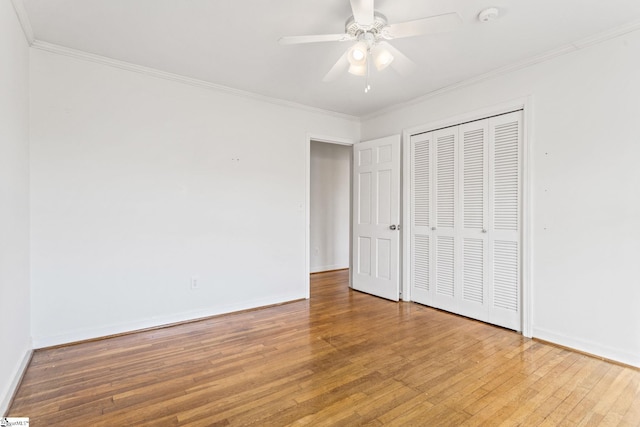 unfurnished bedroom with light wood finished floors, a closet, baseboards, and crown molding