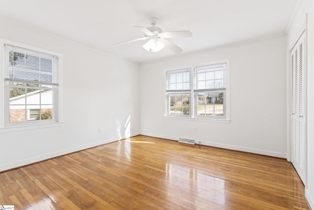 unfurnished bedroom with multiple windows, wood-type flooring, visible vents, and crown molding