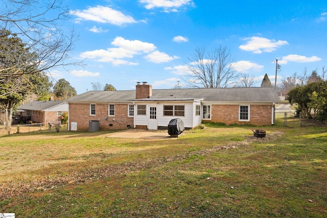 rear view of property with brick siding, a chimney, fence, and a yard