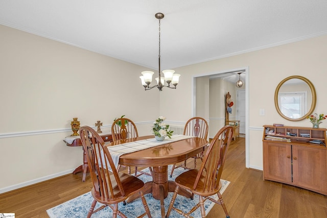 dining space with light wood-style floors, baseboards, crown molding, and an inviting chandelier