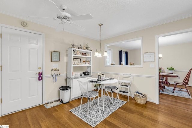 dining room with light wood-style flooring, baseboards, crown molding, and ceiling fan with notable chandelier