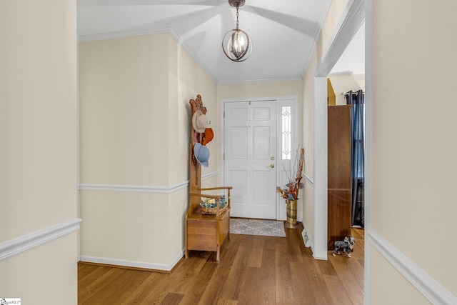 entrance foyer with crown molding, an inviting chandelier, and wood finished floors