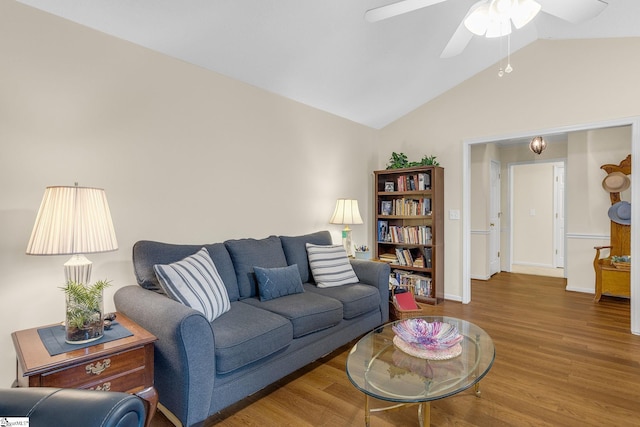 living area featuring a ceiling fan, lofted ceiling, baseboards, and wood finished floors