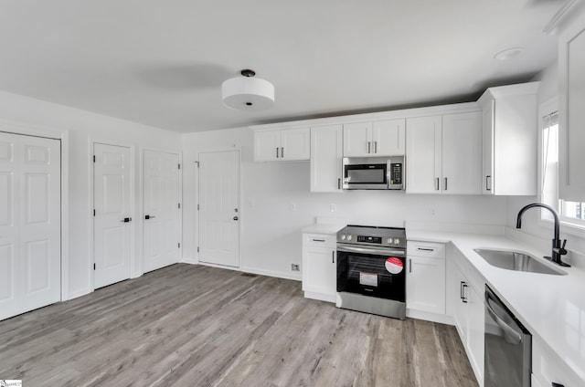 kitchen featuring light countertops, appliances with stainless steel finishes, a sink, and white cabinets