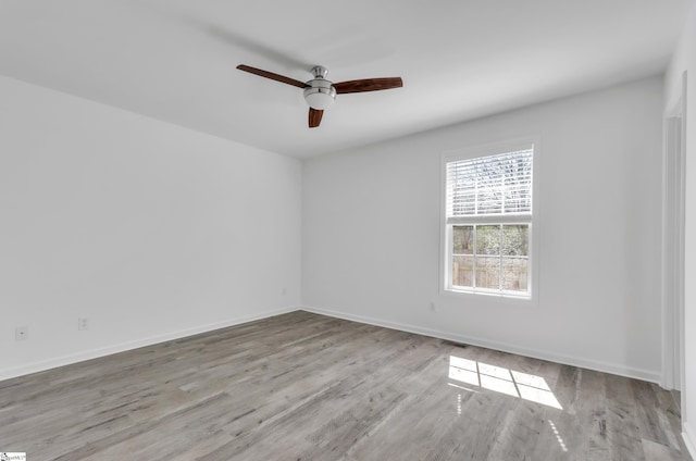 spare room with ceiling fan, visible vents, baseboards, and wood finished floors