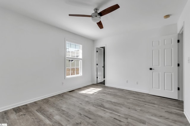 interior space with ceiling fan, wood finished floors, visible vents, and baseboards