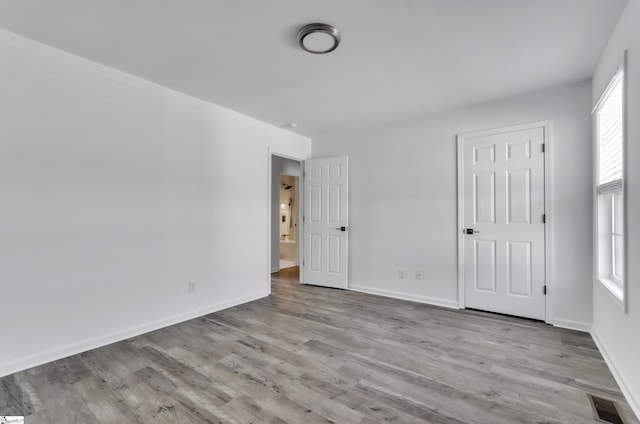 unfurnished bedroom featuring visible vents, baseboards, and wood finished floors