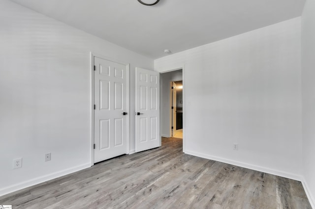 unfurnished bedroom with a closet, baseboards, and wood finished floors