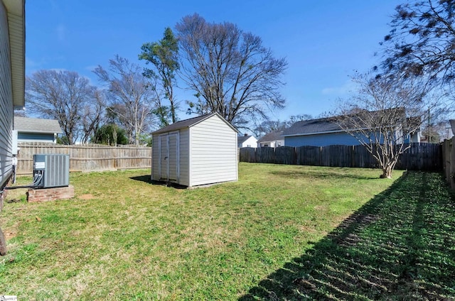 view of yard with a shed, central AC unit, a fenced backyard, and an outdoor structure