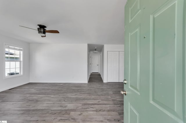 unfurnished room featuring baseboards, a ceiling fan, and wood finished floors