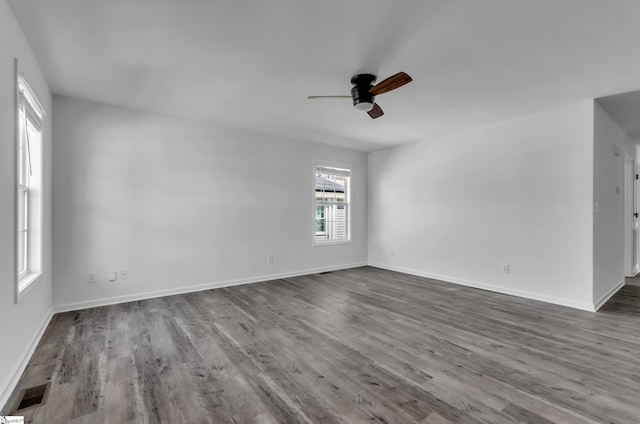 unfurnished room featuring visible vents, baseboards, dark wood finished floors, and a ceiling fan