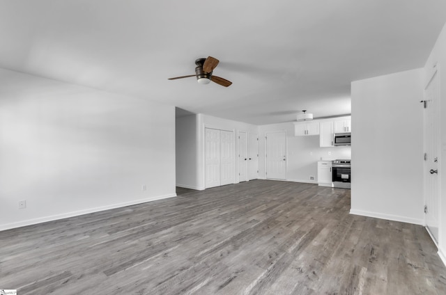 unfurnished living room featuring baseboards, a ceiling fan, and wood finished floors