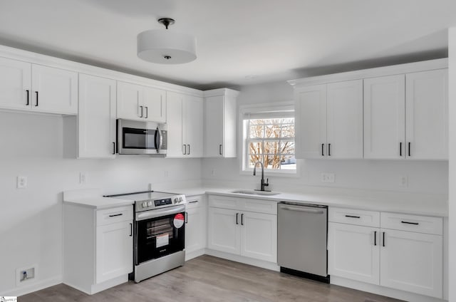 kitchen featuring appliances with stainless steel finishes, light countertops, white cabinetry, and a sink