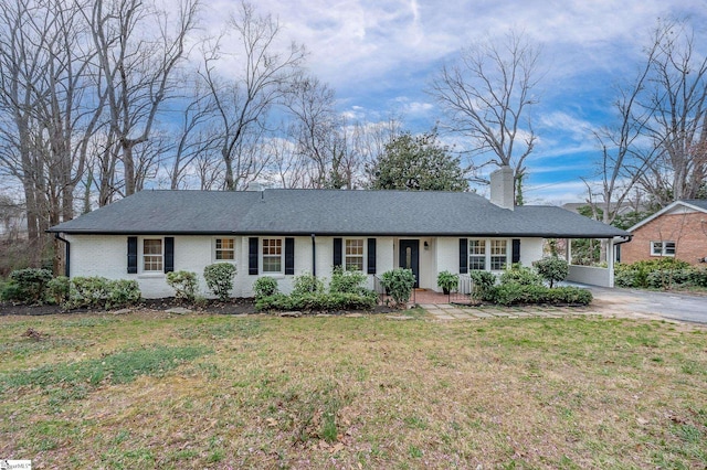 ranch-style house with a carport, brick siding, a chimney, and a front lawn