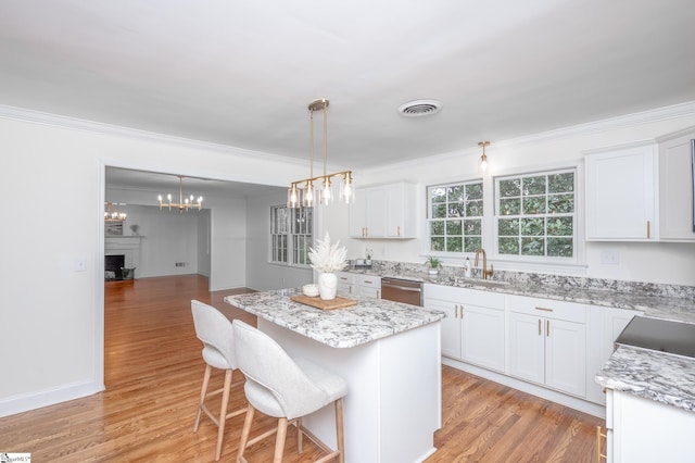 kitchen with light wood finished floors, a fireplace, white cabinetry, and a center island