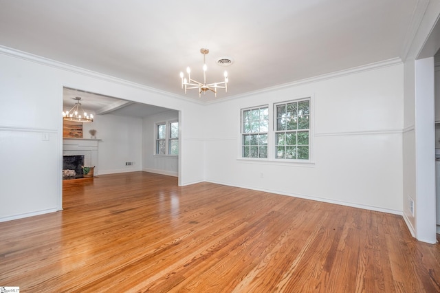 unfurnished living room with a chandelier, crown molding, a fireplace, and light wood-style flooring