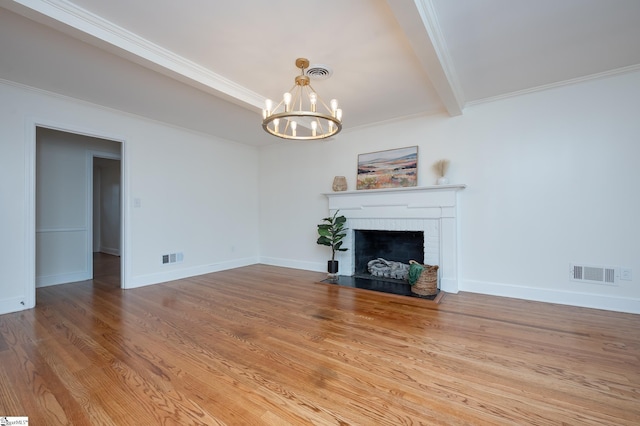 unfurnished living room featuring a fireplace, visible vents, an inviting chandelier, wood finished floors, and baseboards