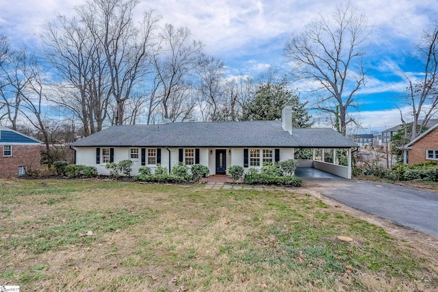 ranch-style home with an attached carport, brick siding, driveway, a chimney, and a front yard