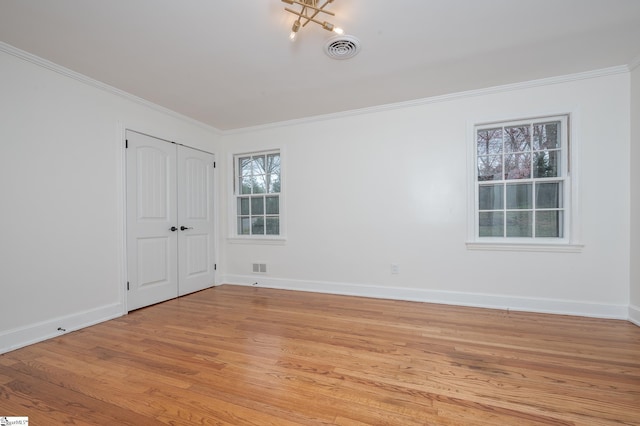 unfurnished room with light wood-style flooring, visible vents, baseboards, and ornamental molding